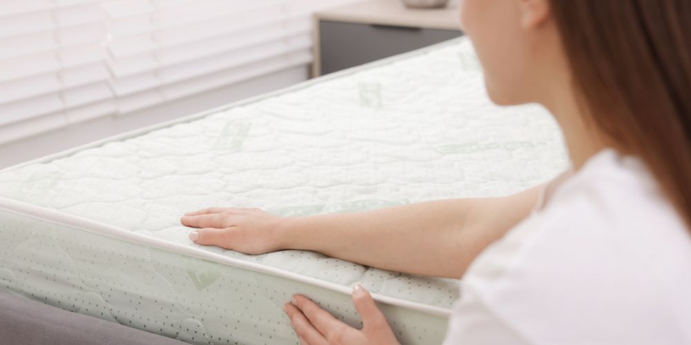 Woman running her hand across a cleaned mattress